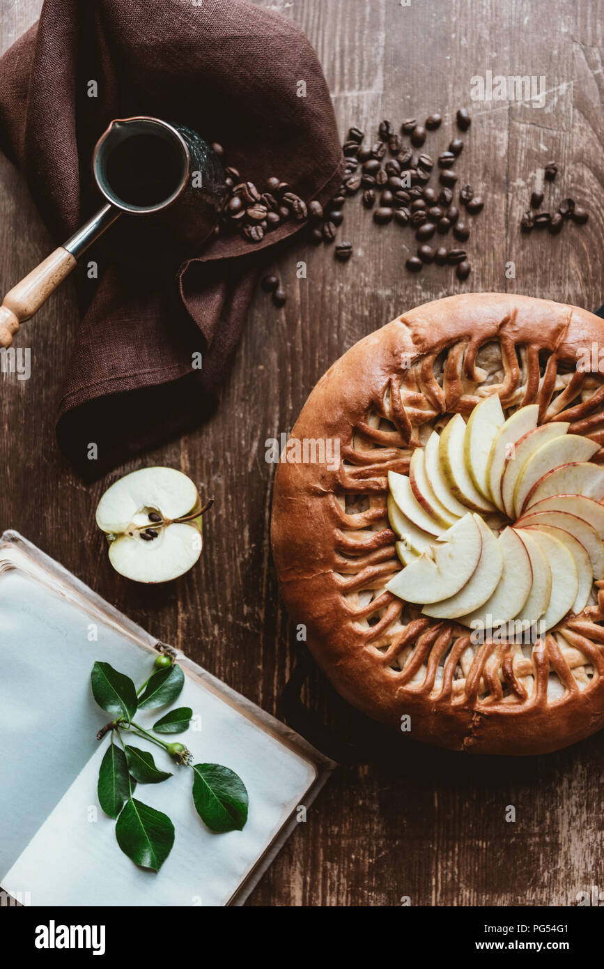 flat lay with homemade apple pie, coffee maker, empty notebook and fresh apples on wooden tabletop Stock Photo