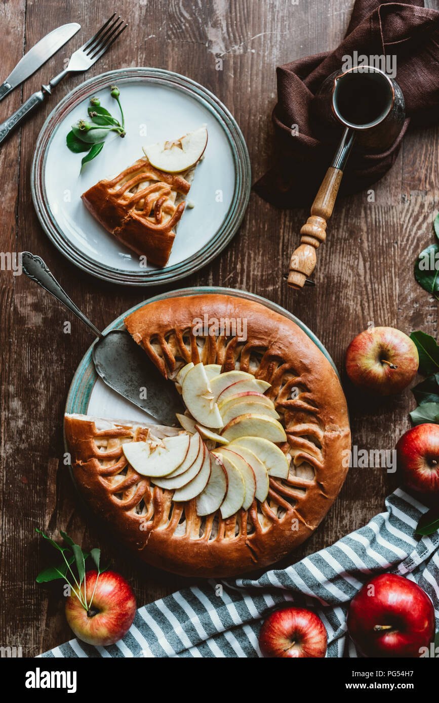 flat lay with piece of homemade apple pie, cutlery and coffee maker arranged on wooden surface Stock Photo