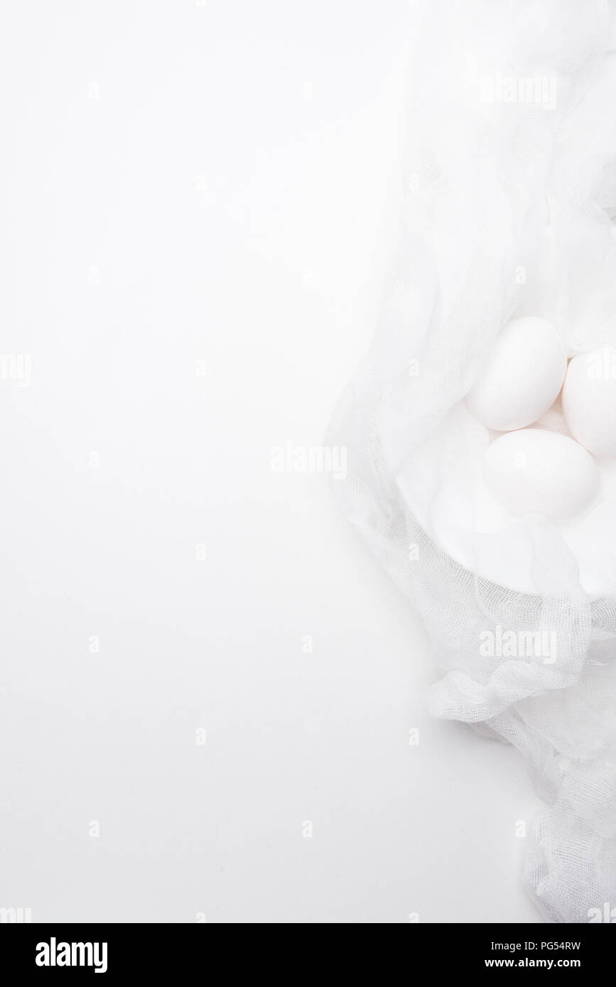 top view of chicken eggs in cheesecloth on white surface Stock Photo