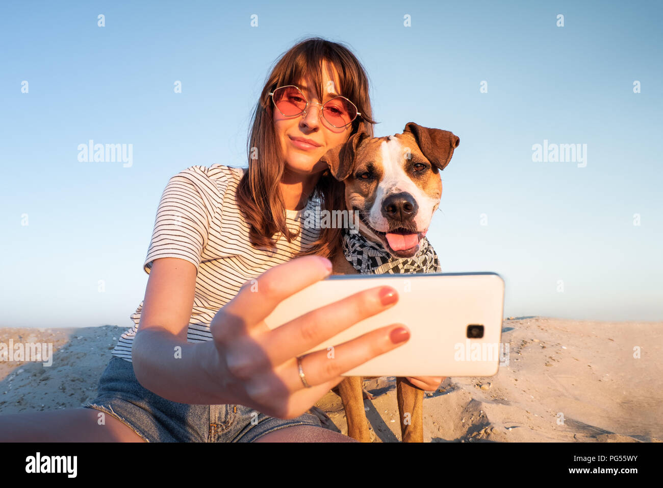 Best friends concept: human taking a selfie with dog. Young female makes self portrait with her puppy outdoors on a beach Stock Photo