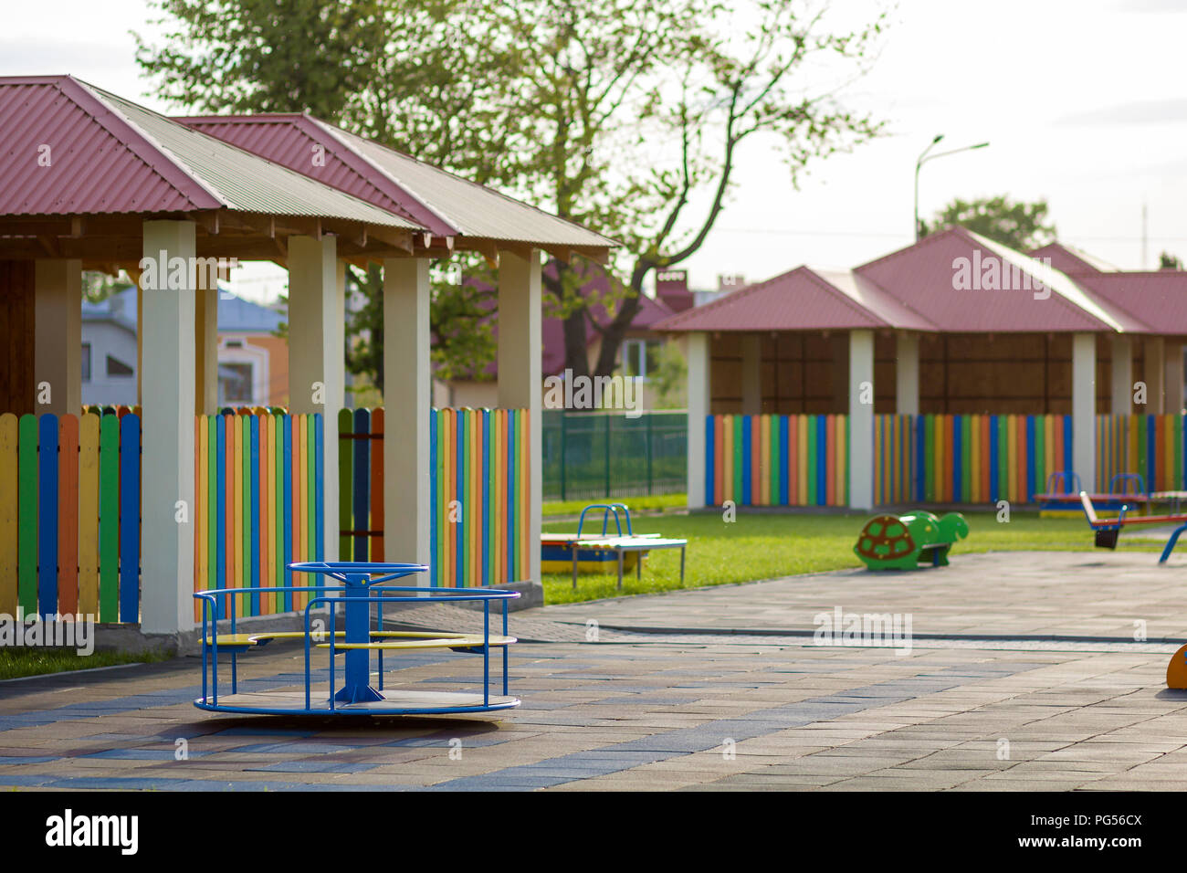Beautiful new modern playground in kindergarten with soft pavement, bright new multicolored alcoves, swings, slides, benches, roundabout and sandbox.  Stock Photo