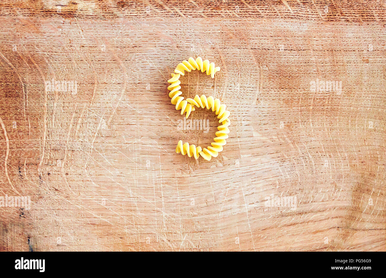 S letter done with pasta fusilli on a wooden chopping board Stock Photo