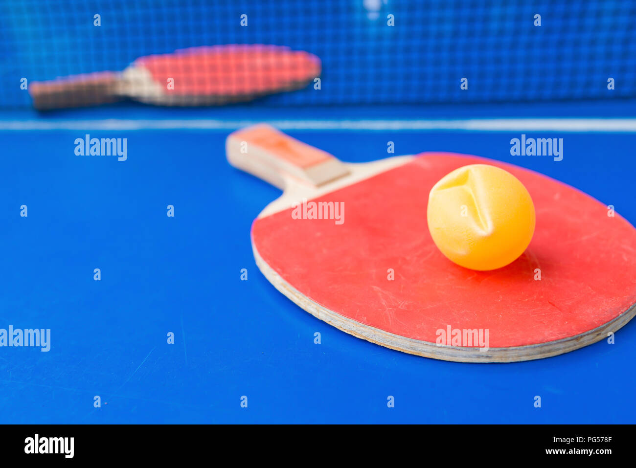 pingpong rackets and ball and net on a blue pingpong table Stock Photo