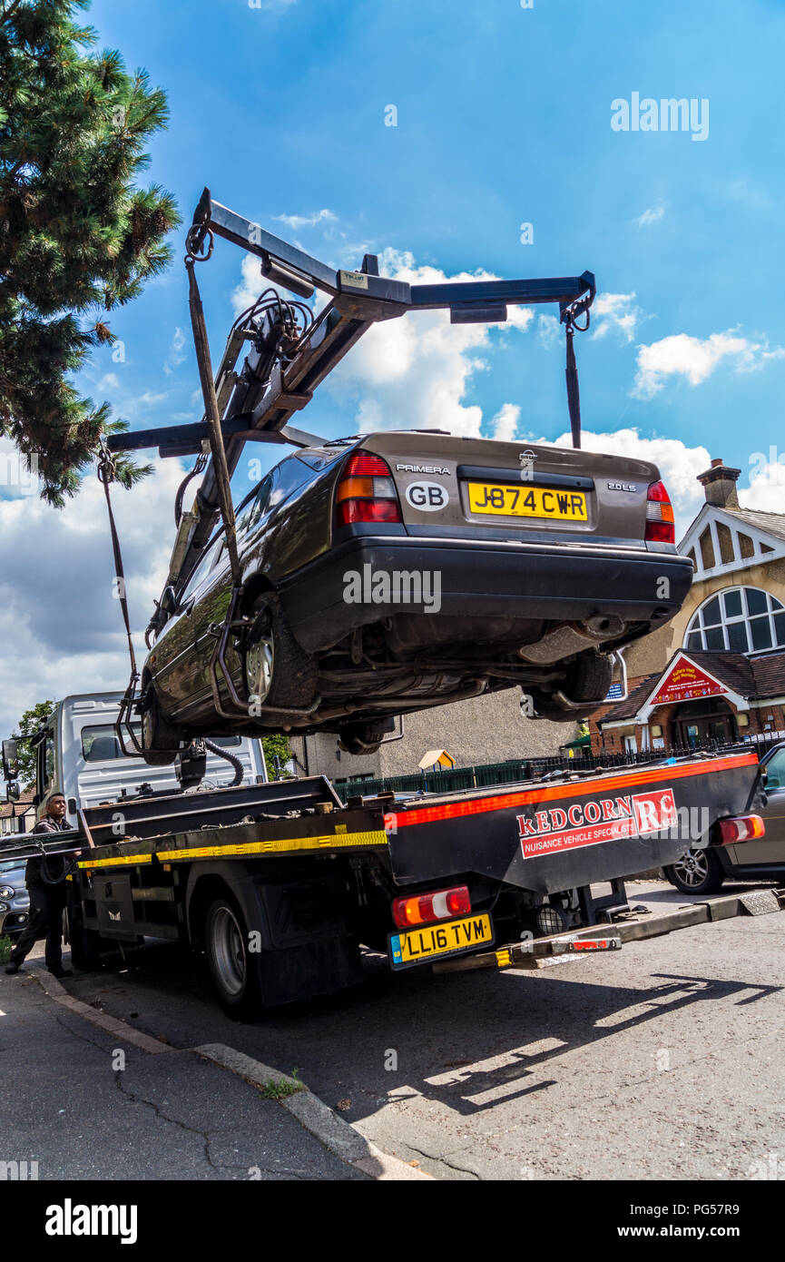 A 1992 Nissan Primera 2.0 LSI Automatic hatchback car being lifted onto a Mercedes Atego recovery lorry for recycling, South Woodford, London, England Stock Photo