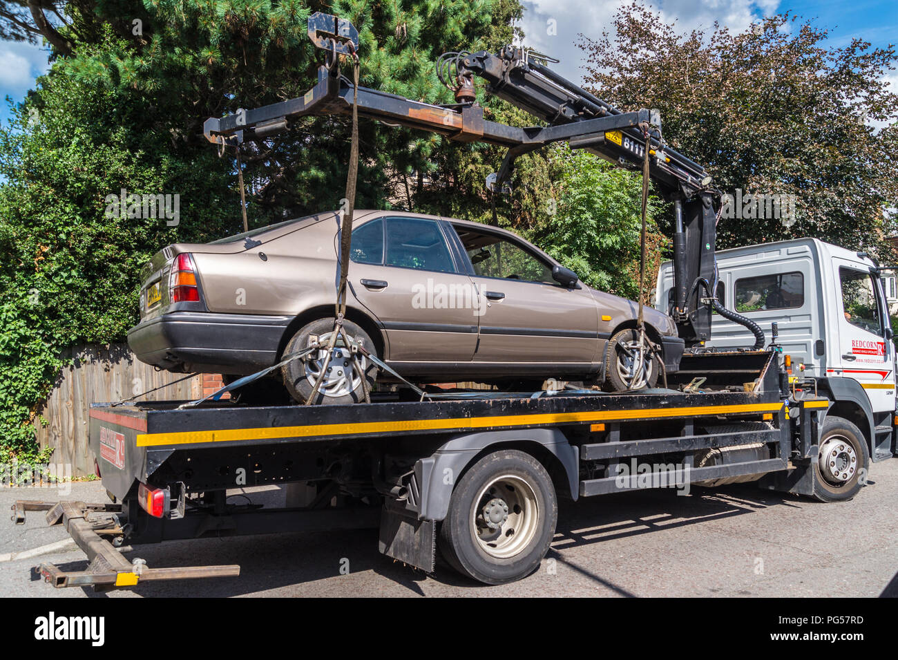 A 1992 Nissan Primera 2.0 LSI Automatic hatchback car being lifted onto a Mercedes Atego recovery lorry for recycling, South Woodford, London, England Stock Photo