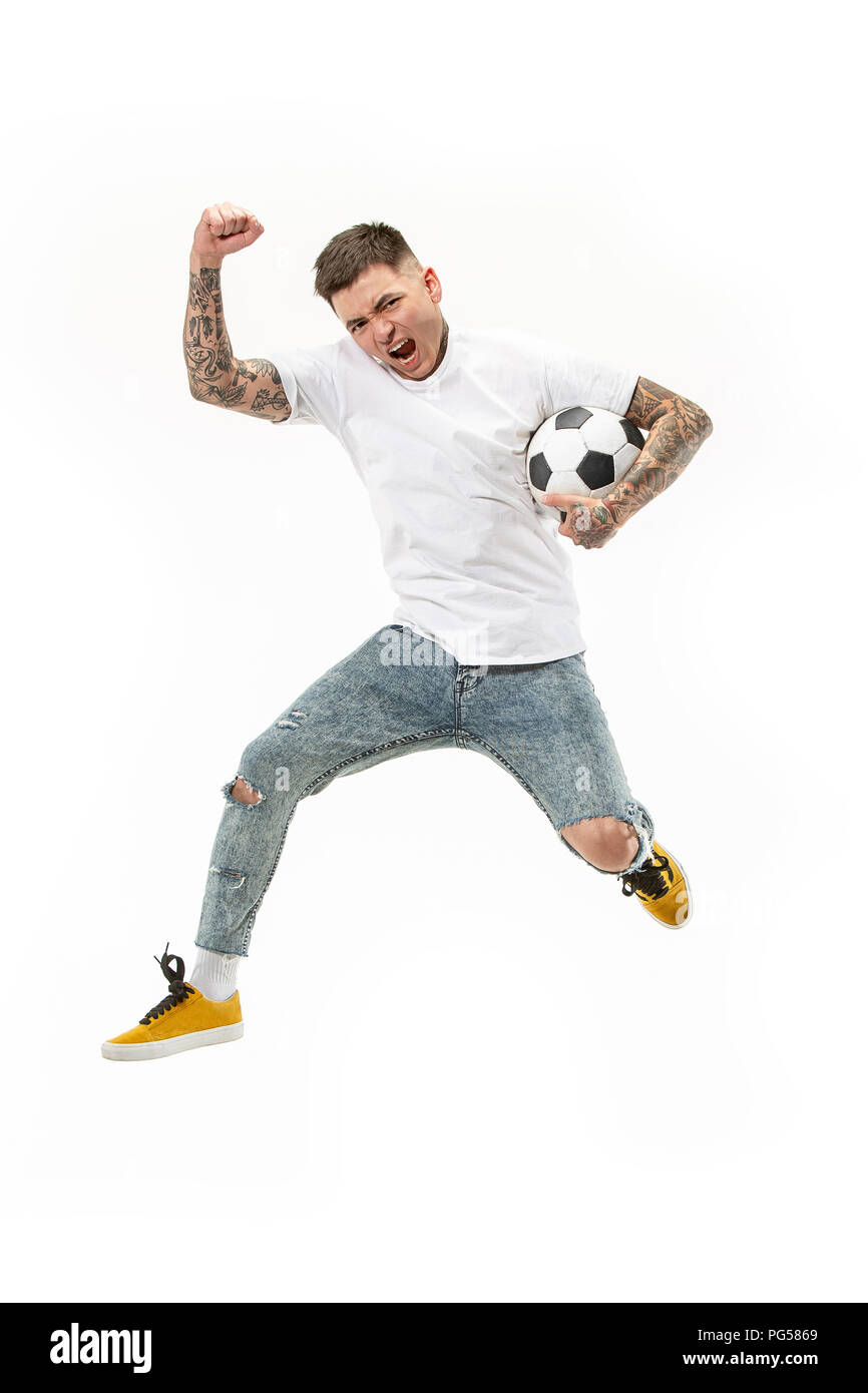 Forward to the victory.The young man as soccer football player jumping and kicking the ball at studio on a white background. Football fan and world championship concept. Human emotions concepts Stock Photo