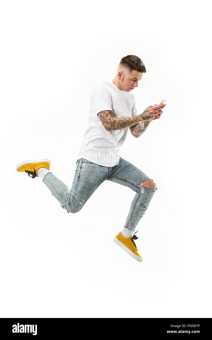 always on mobile. Full length of handsome young man taking phone while jumping against orange studio background. Mobile, motion, movement, business concepts Stock Photo