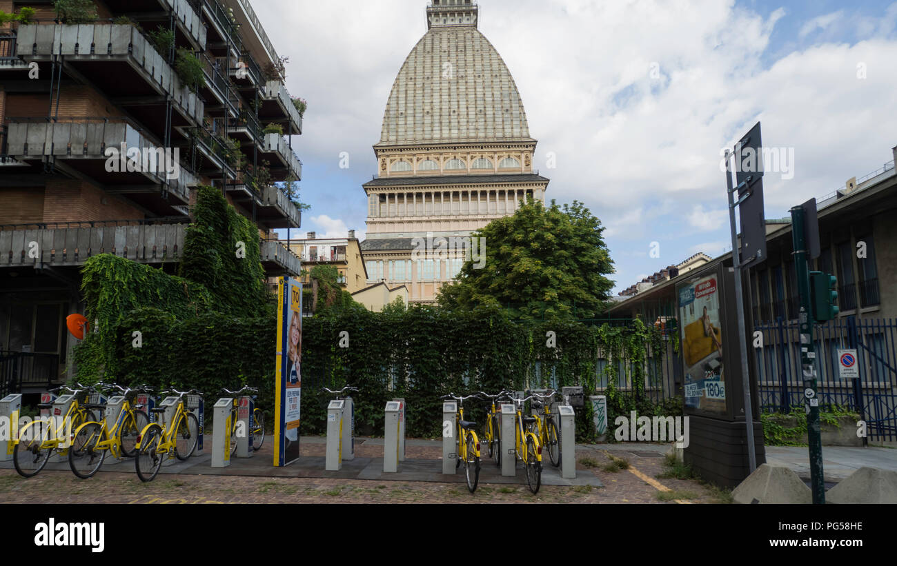 August 2018: Mole Antonelliana among the buildings. In the foreground you can see a Bike Sharing service. The day is clear with some clouds to refresh Stock Photo