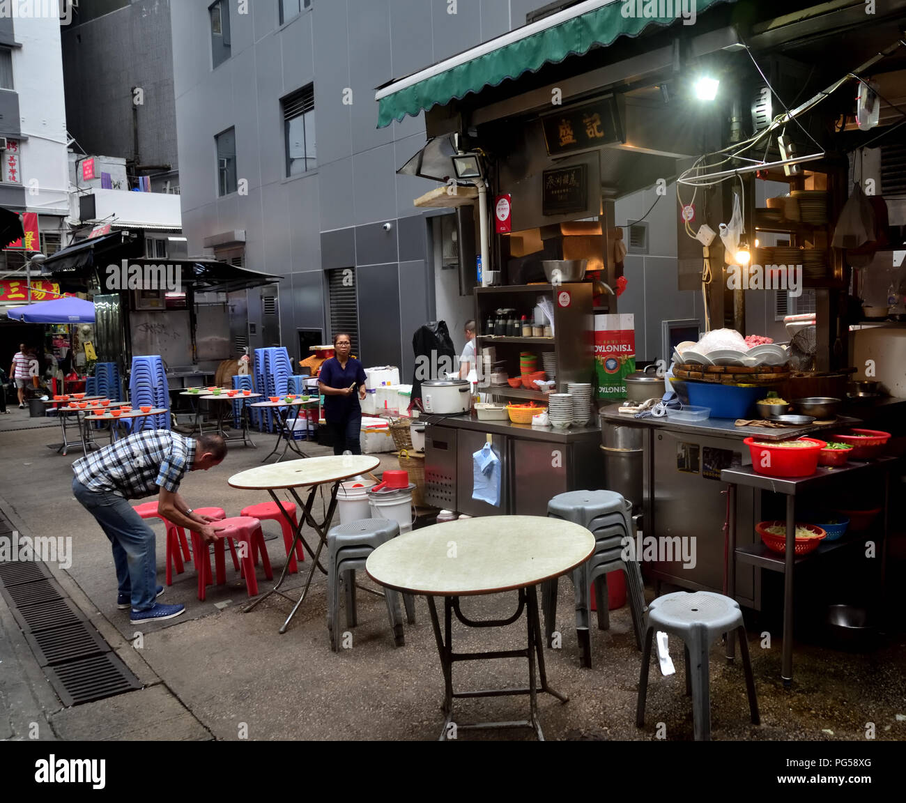 Workers of outdoor food stall have tables set up for night time business, Central District, Hong Kong Stock Photo