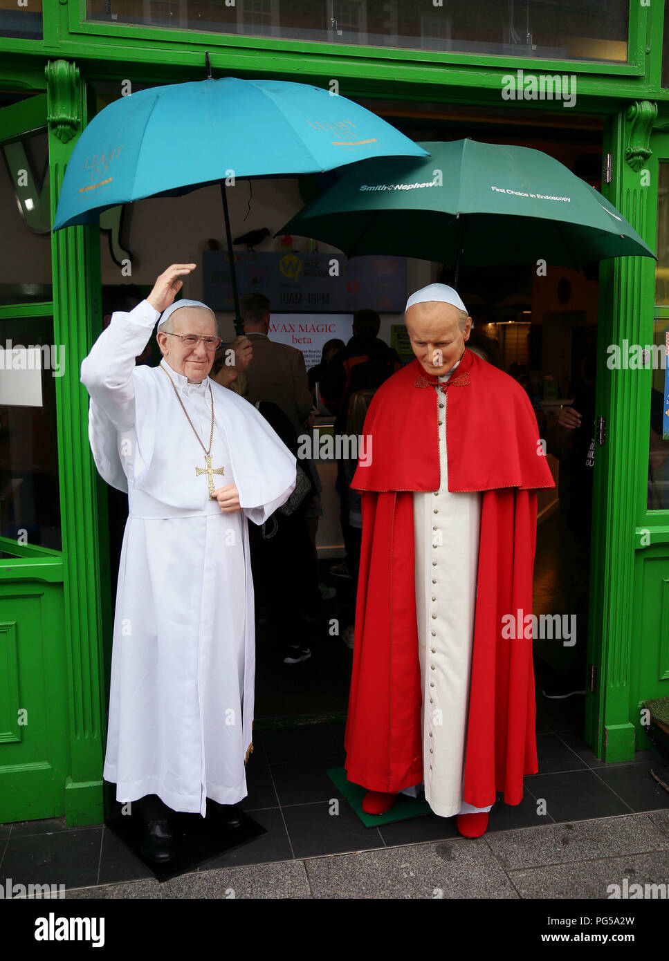A newly unveiled wax work of Pope Francis (left) and the waxwork of Pope John Paul II are sheltered from the rain at the National Wax Museum Plus in Dublin where they also unveiled a newly refurbished original 1979 Pope Mobile ahead of Pope Francis&Otilde; Visit To Ireland. Stock Photo
