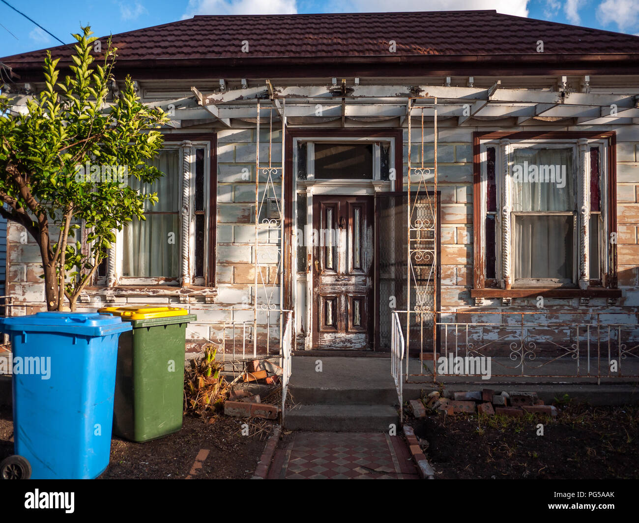Old grungy residential house with rubbish bin in front yard. Melbourne's suburban house in Footscray VIC Australia. Stock Photo