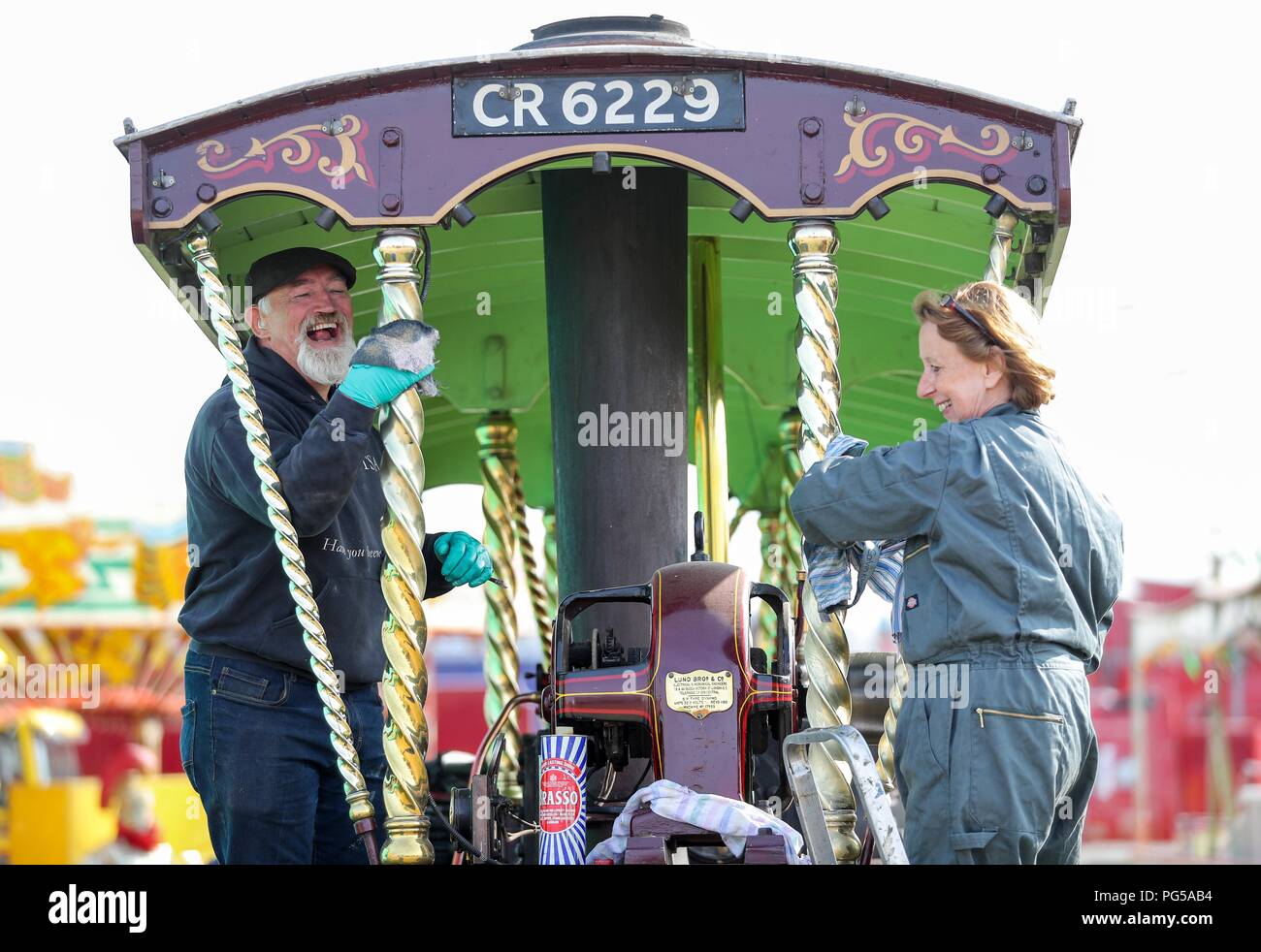 Charlie Harris (left) and Amanda Gilbey polish the Burrell Showman's tractor 'St Benard' at the Great Dorset Steam Fair, at Tarrant Hinton, near Blandford Forum, where hundreds of steam-driven traction engines and heavy mechanical equipment from all eras, gather for the annual show which runs until Bank Holiday Monday and this year celebrates its 50th anniversary. Stock Photo