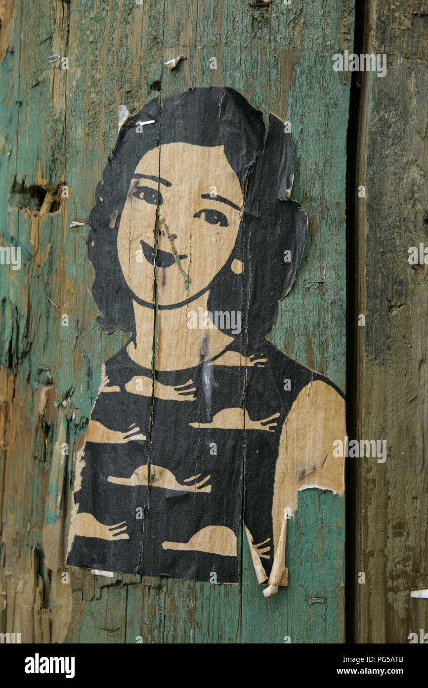 Small paste-up of a woman on a wooden post Stock Photo