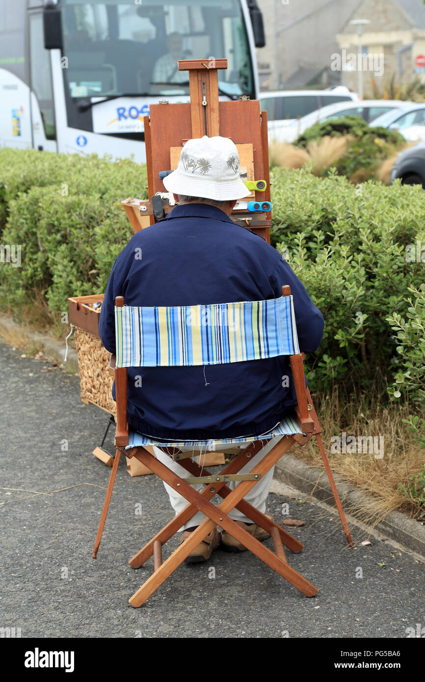 Back view of artist painting plein aire next to Quai Charles de Gaulle, Roscoff, Finistere, Brittany, France Stock Photo