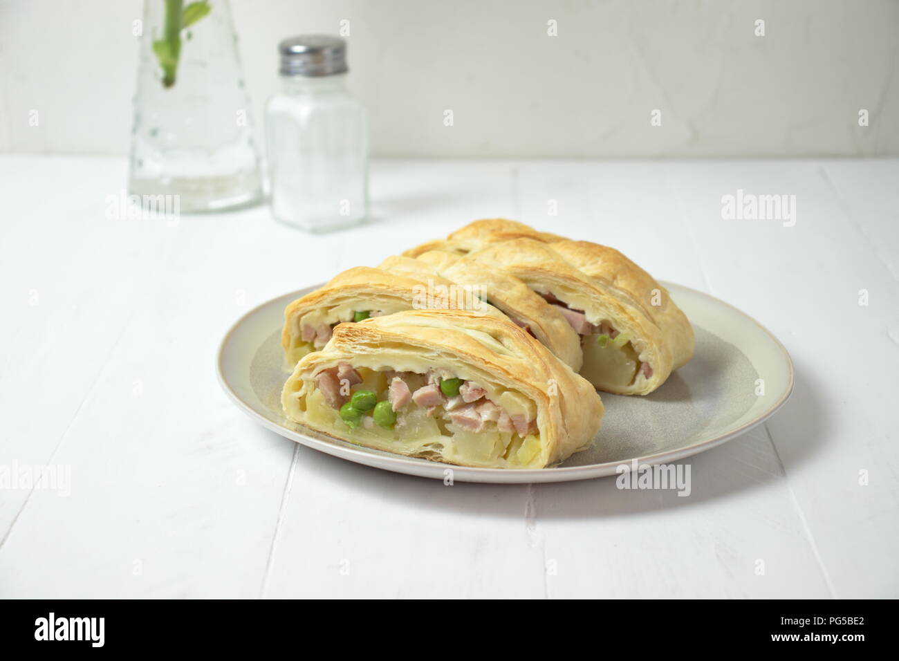 Salty braid made of puff pastry filled with potatoes, ham and peas Stock Photo
