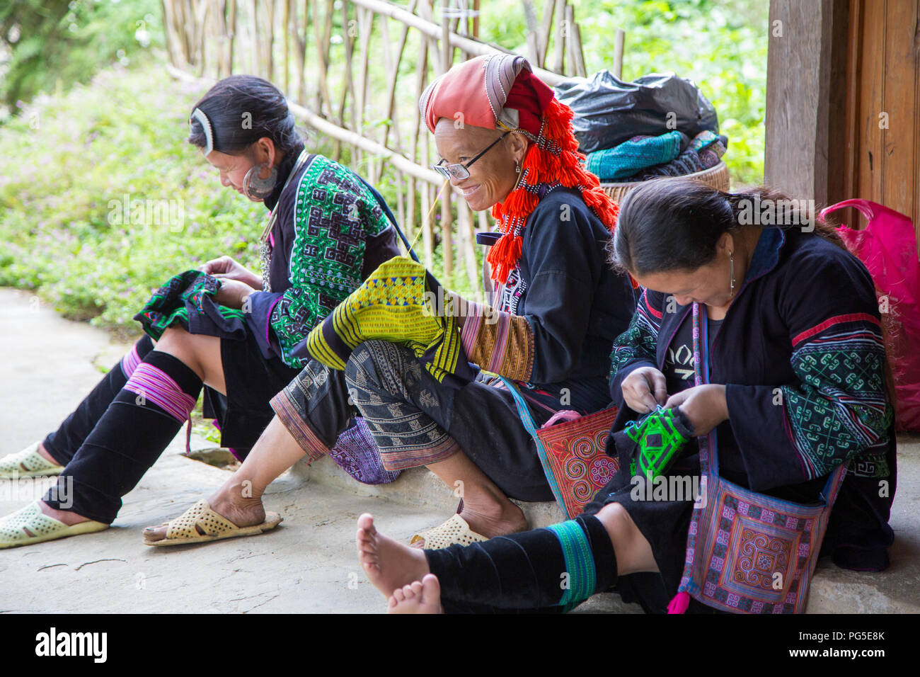 Three women of different cultural communities working on their embroidery near Sapa, northern Vietnam Stock Photo
