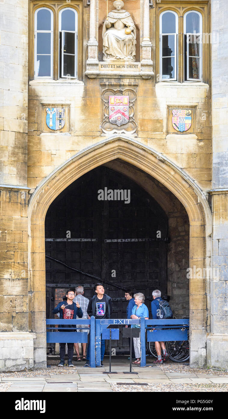 Visitors in the porch below the statue of Queen Elizabeth I on the wall of Queen's Gate at Trinity college, Cambridge University, England. Stock Photo