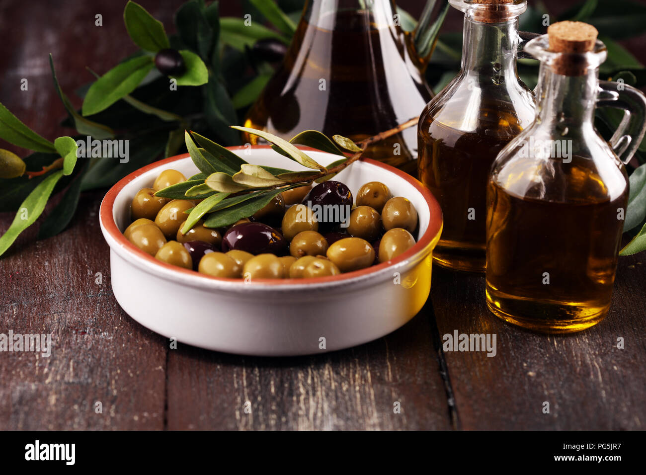 Bottle virgin olive oil and oil in a bowl with some olives Stock Photo ...