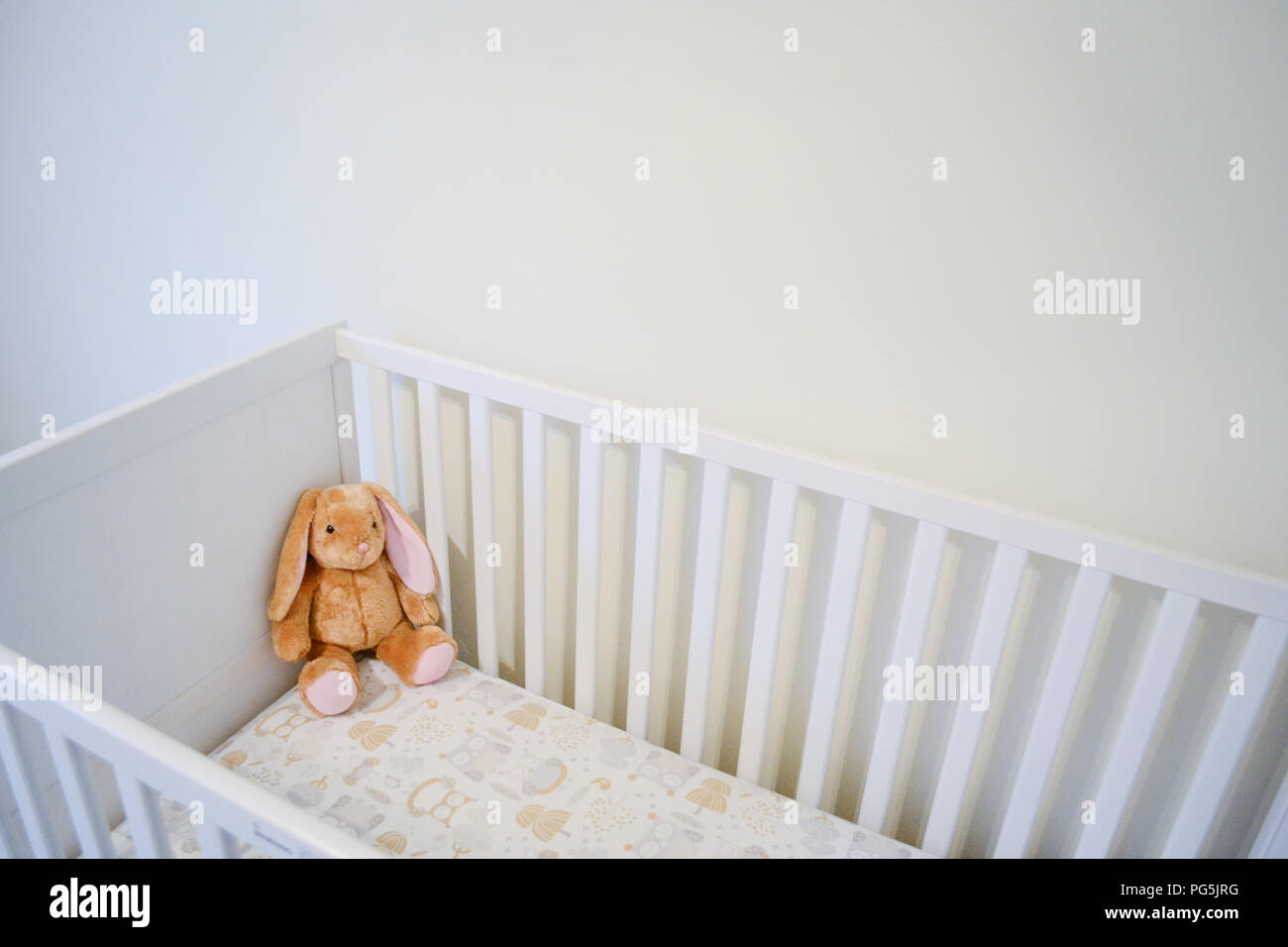 Baby girl's crib. Neutral colors. Owl bed sheet. Ikea SUNDVIK white crib. Converts into a toddler bed. Stuffed animal from Build-A-Bear Workshop. Stock Photo