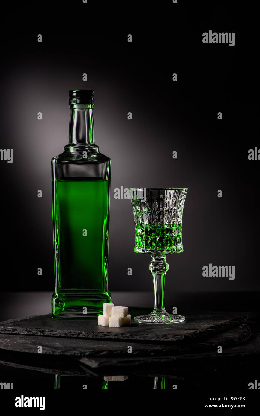 close-up shot of glass and bottle of absinthe with sugar cubes on dark background Stock Photo