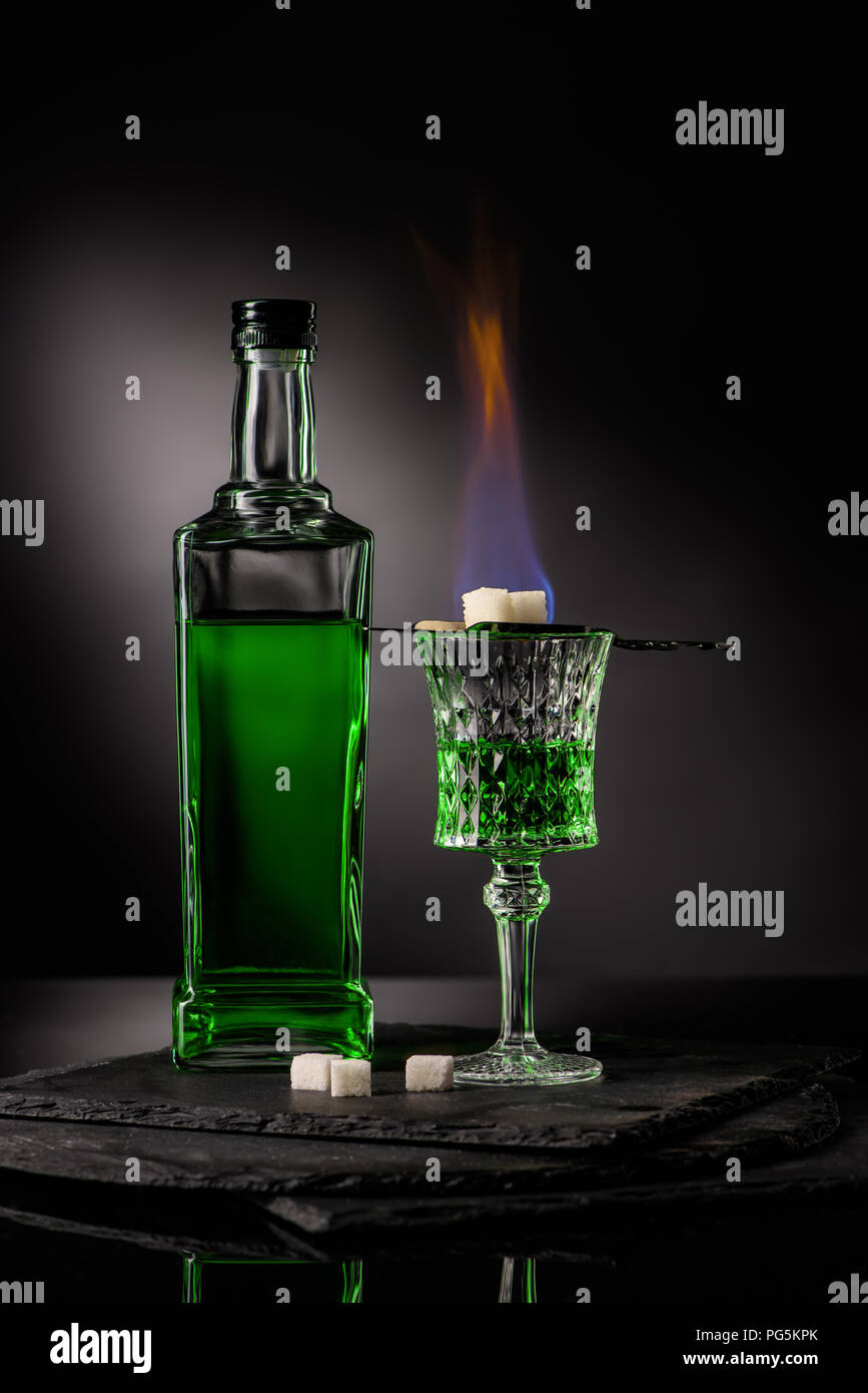 close-up shot of spoon with sugar cubes over burning absinthe in glass on dark background Stock Photo