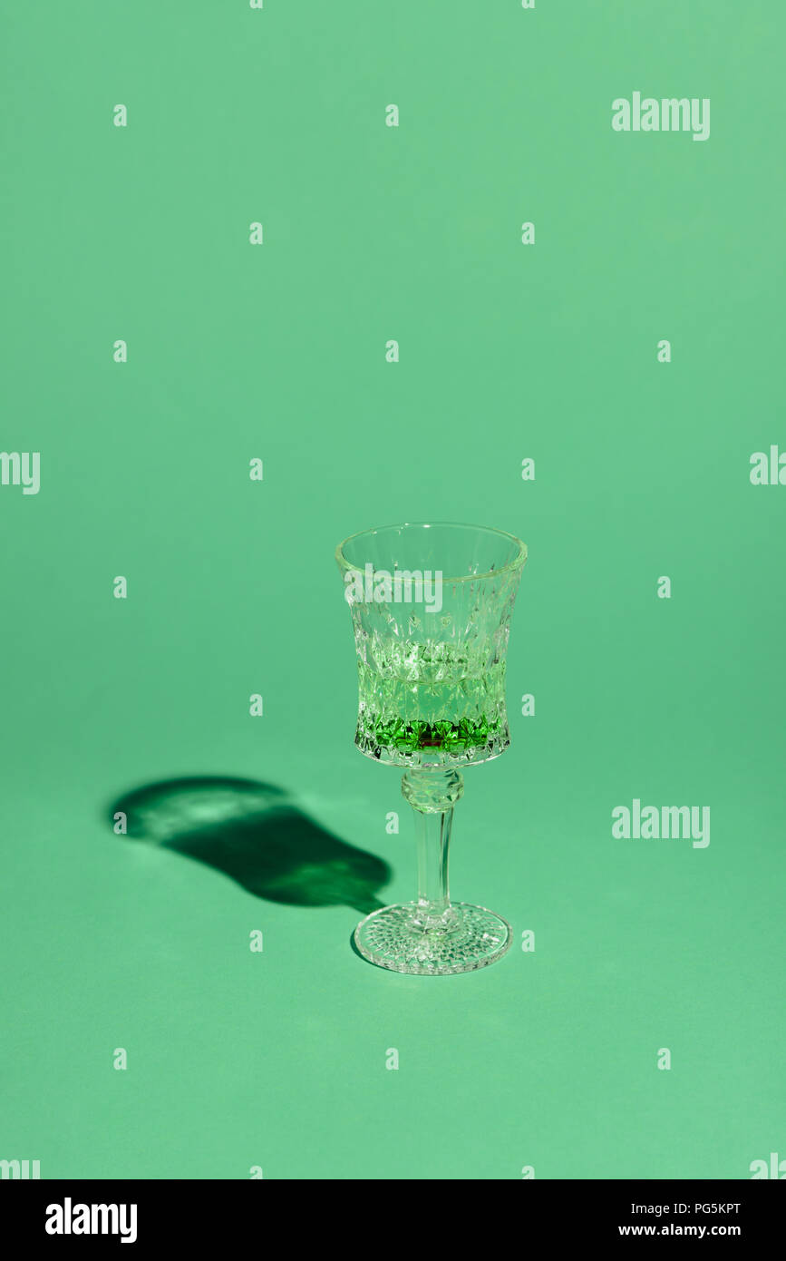 crystal glass of absinthe beverage on green surface Stock Photo