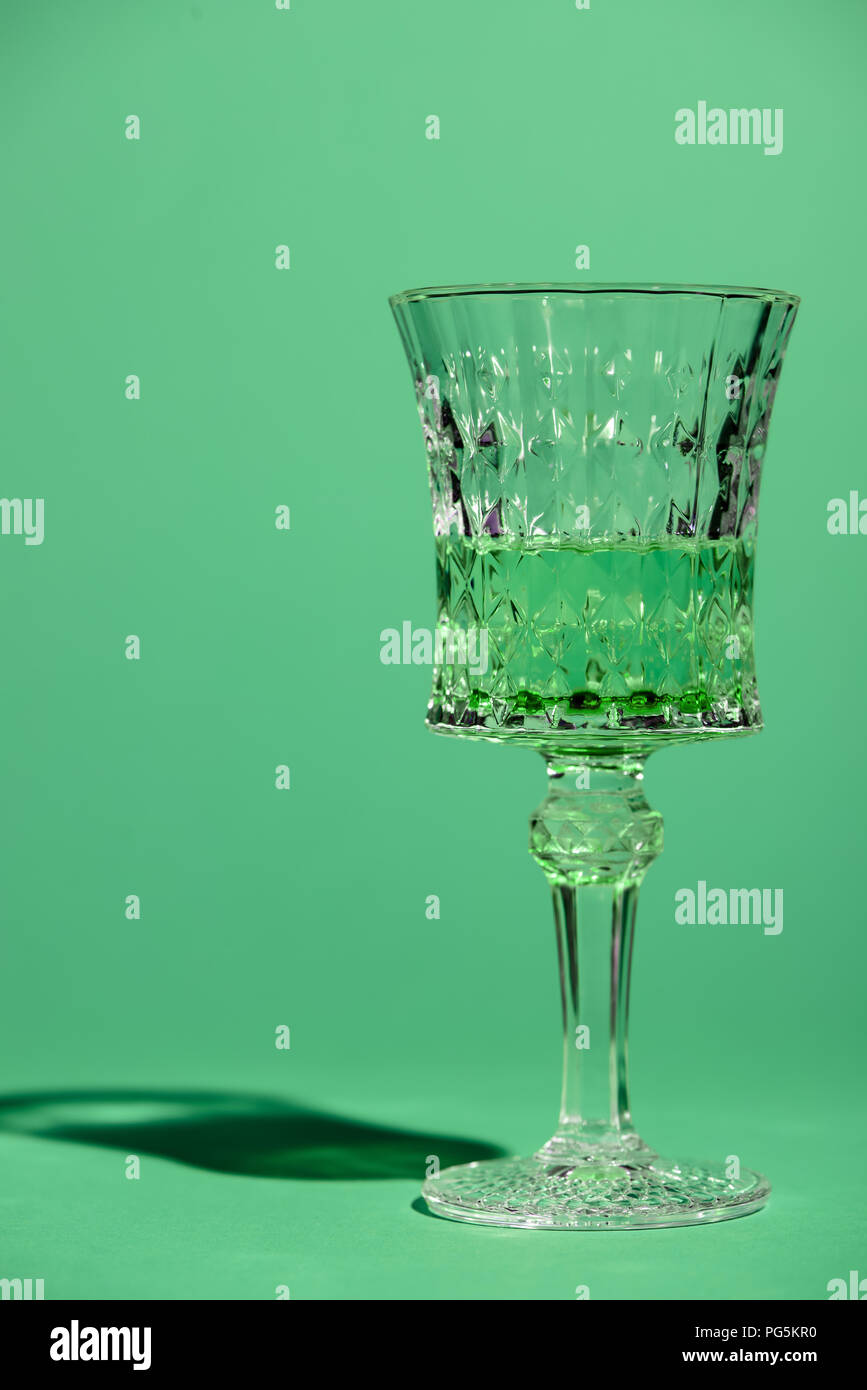 close-up shot of crystal glass of absinthe isolated on green Stock Photo