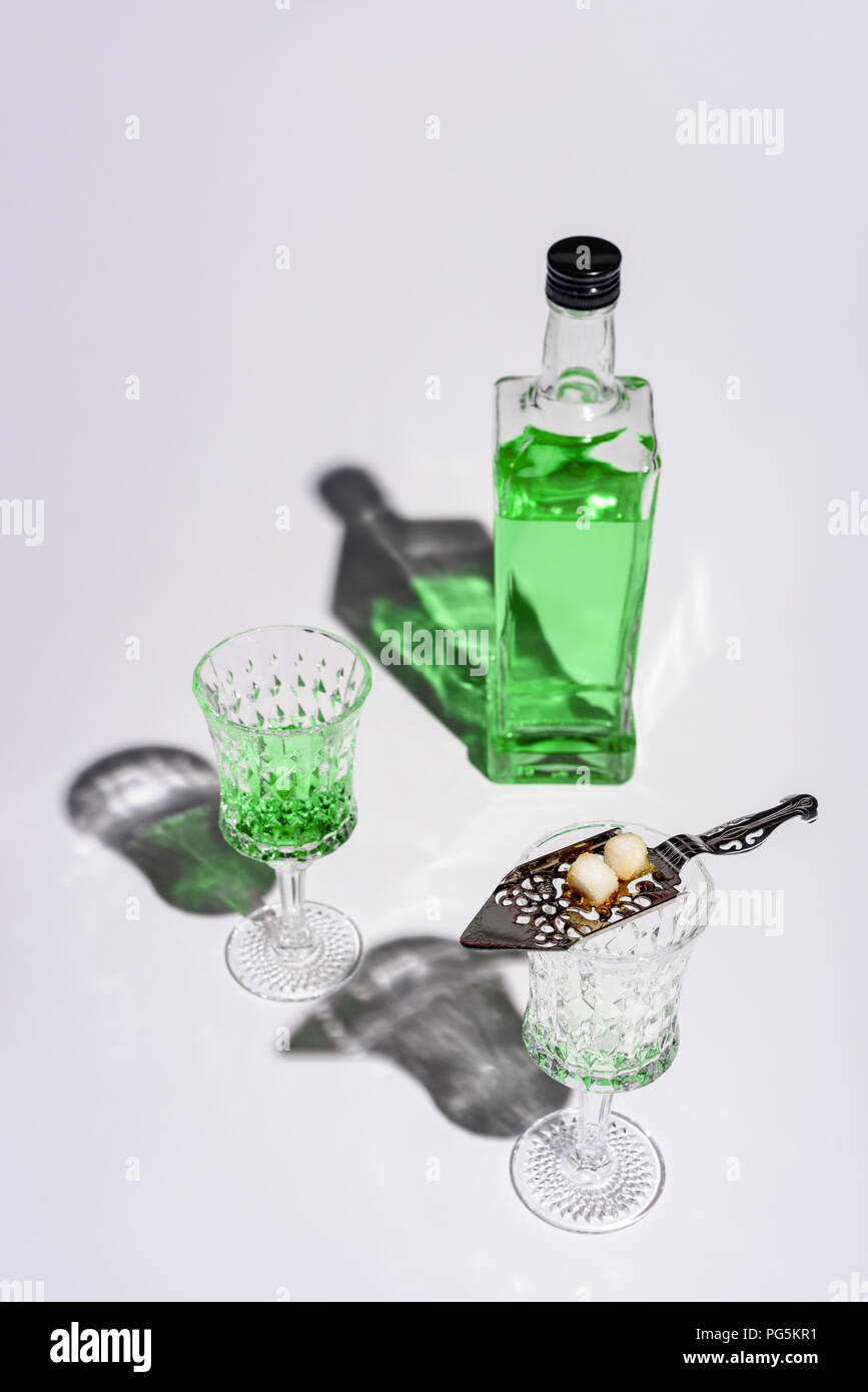crystal glasses with absinthe spoon and bottle of absinthe on white