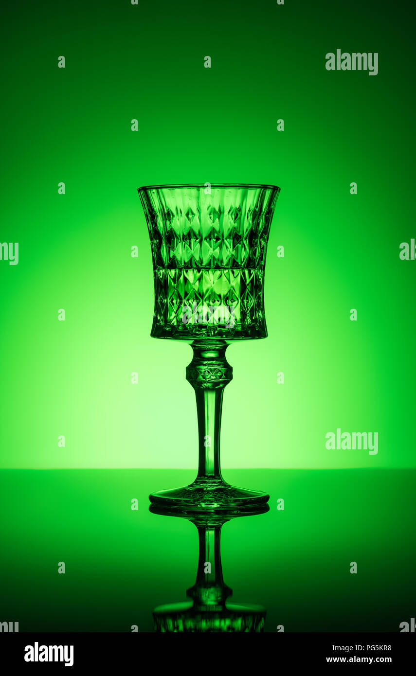 crystal glass of absinthe on reflective surface and dark green background Stock Photo