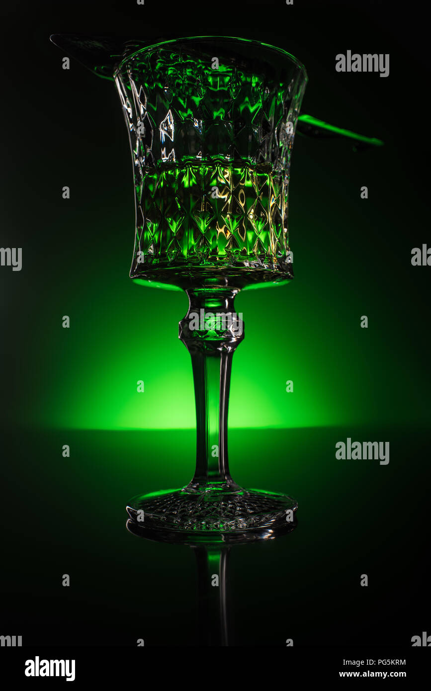 close-up shot of glass with absinthe on reflective surface and dark green background Stock Photo