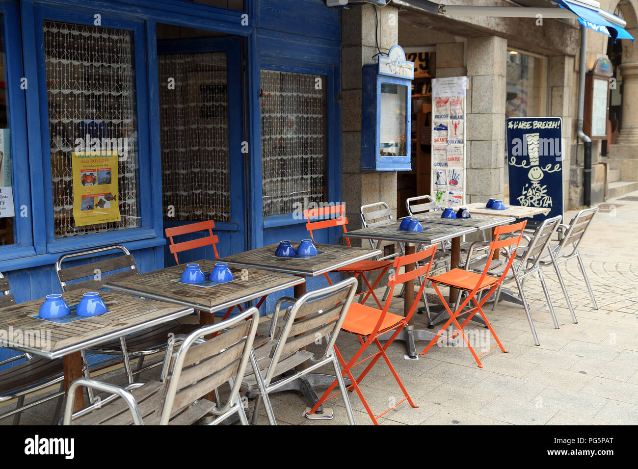 Tables and chairs outside creperie in Rue Admiral Reveillere, Roscoff, Finistere, Brittany, France Stock Photo