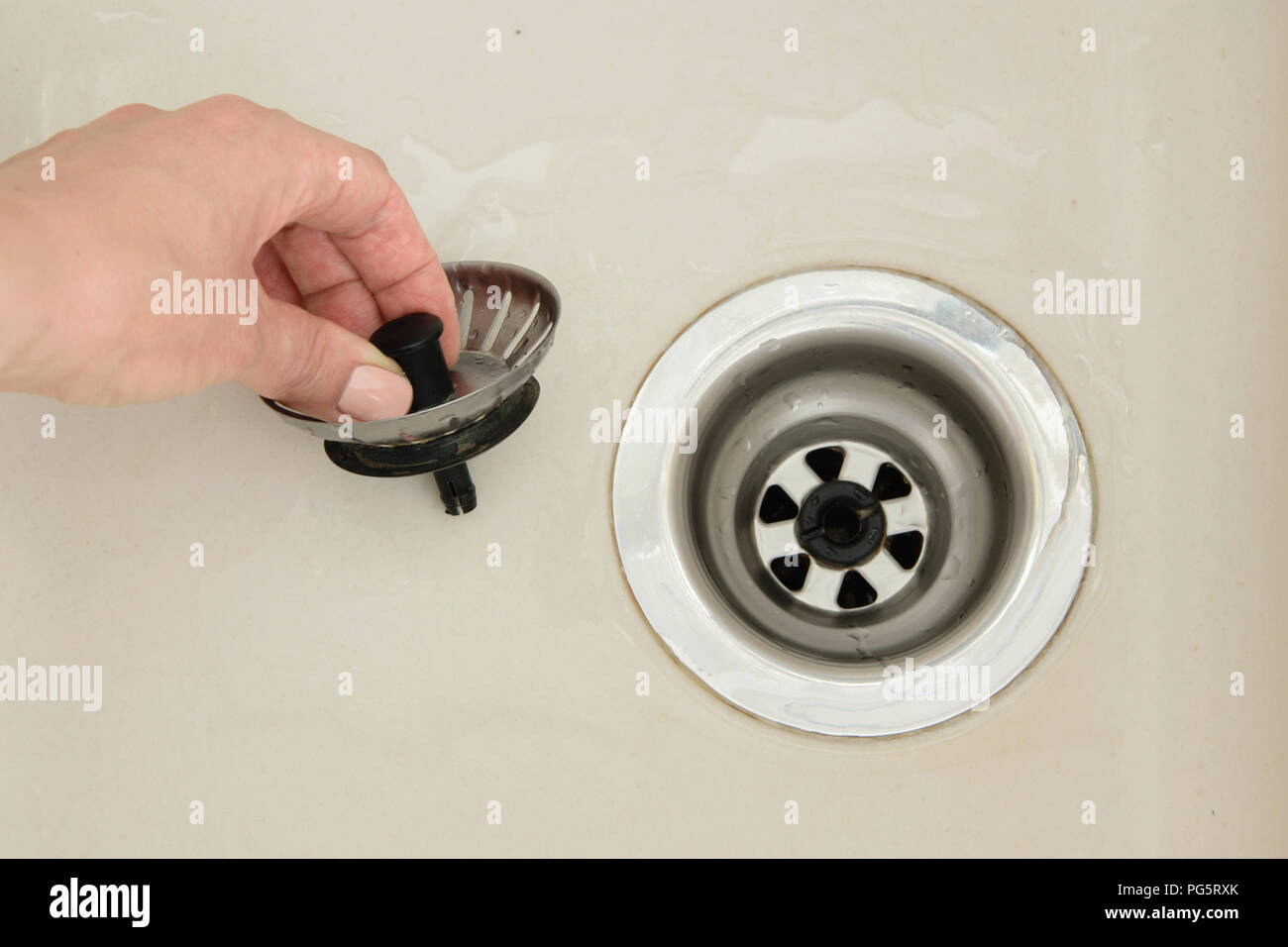 Woman hand pulls close cap of drainage hole of sink to drain water Stock Photo