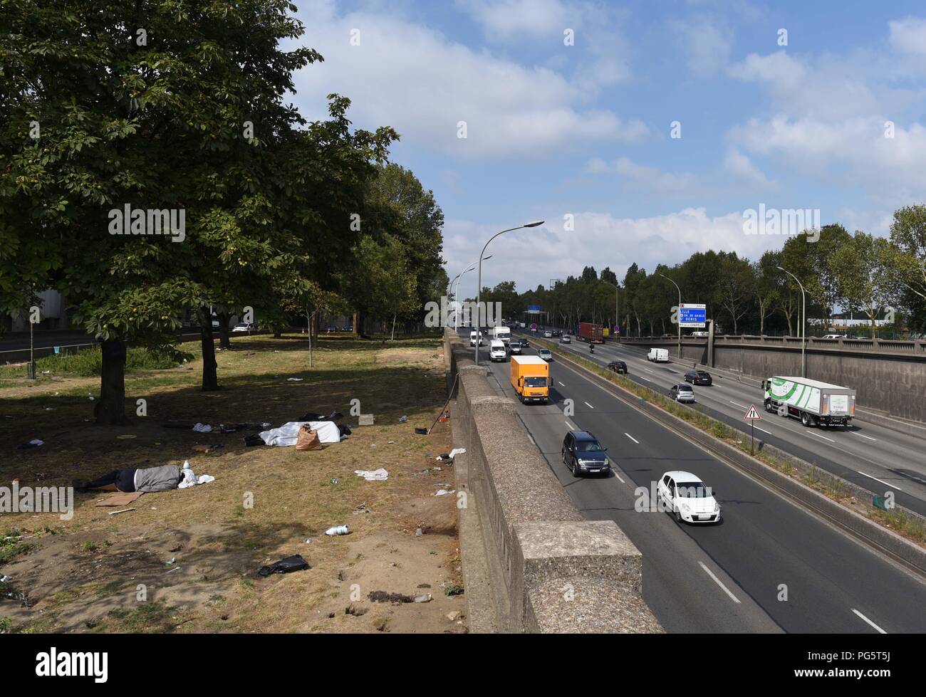 August 14, 2018 - Paris, France: Migrants sleep in a public park near the  peripherique (ring road) between porte de la Chapelle and porte  d'Aubervilliers. Des migrants dorment dans un parc public