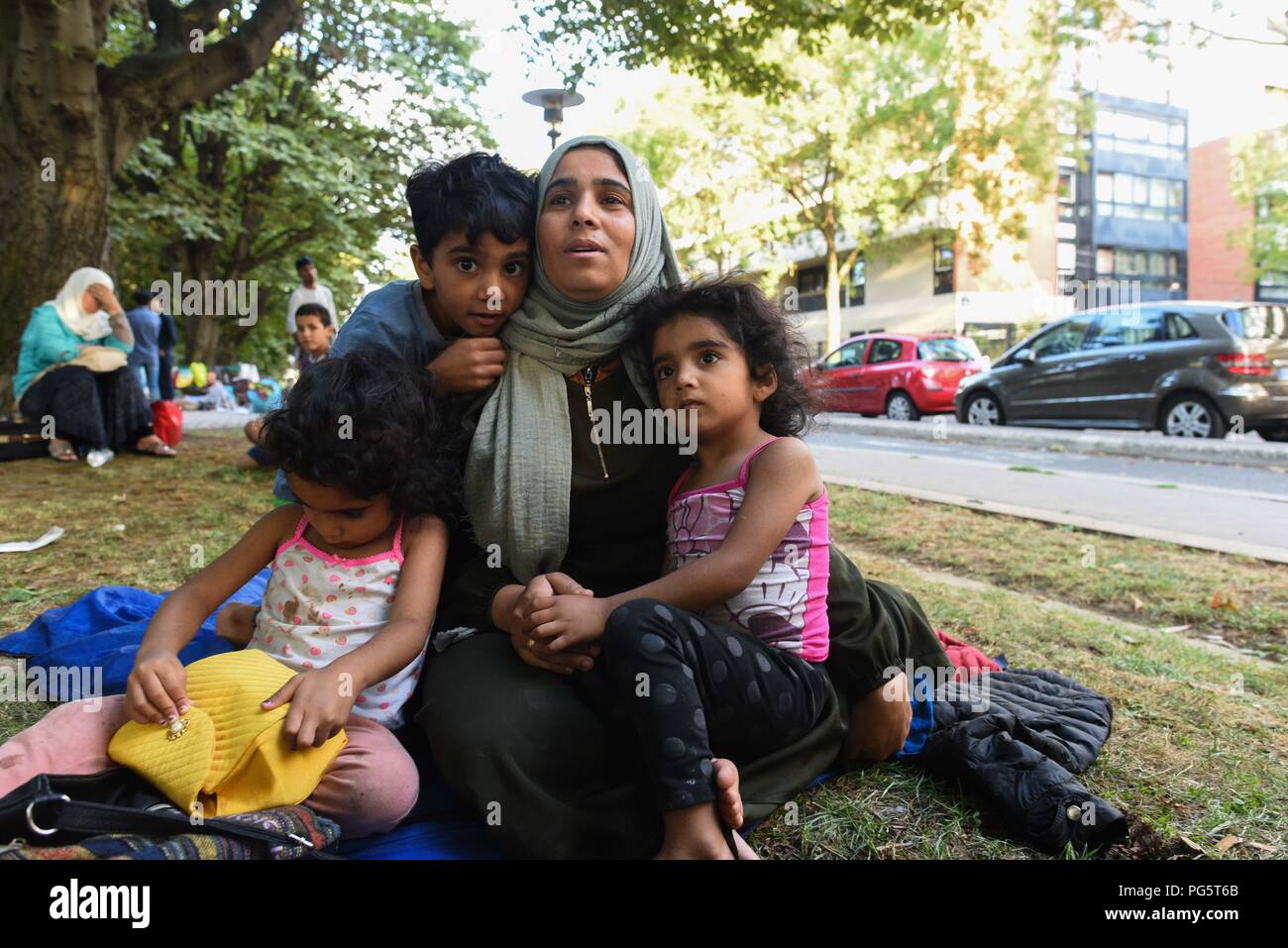 August 14, 2018 - Paris, France: A Syrian family sit in a public park near  porte d'Aubervilliers as they wait for a charity to find them emergency  shelter for the night. The