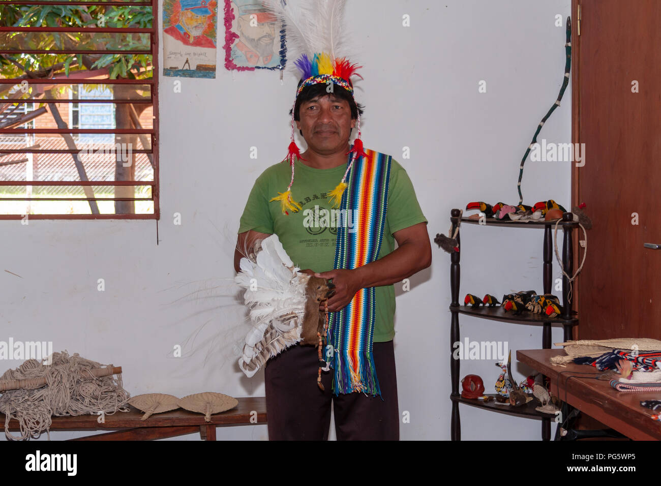 Portrait of Maka indian man with war bonnet showing handicrafts at the village on the outskirts of Asuncion, Paraguay Stock Photo