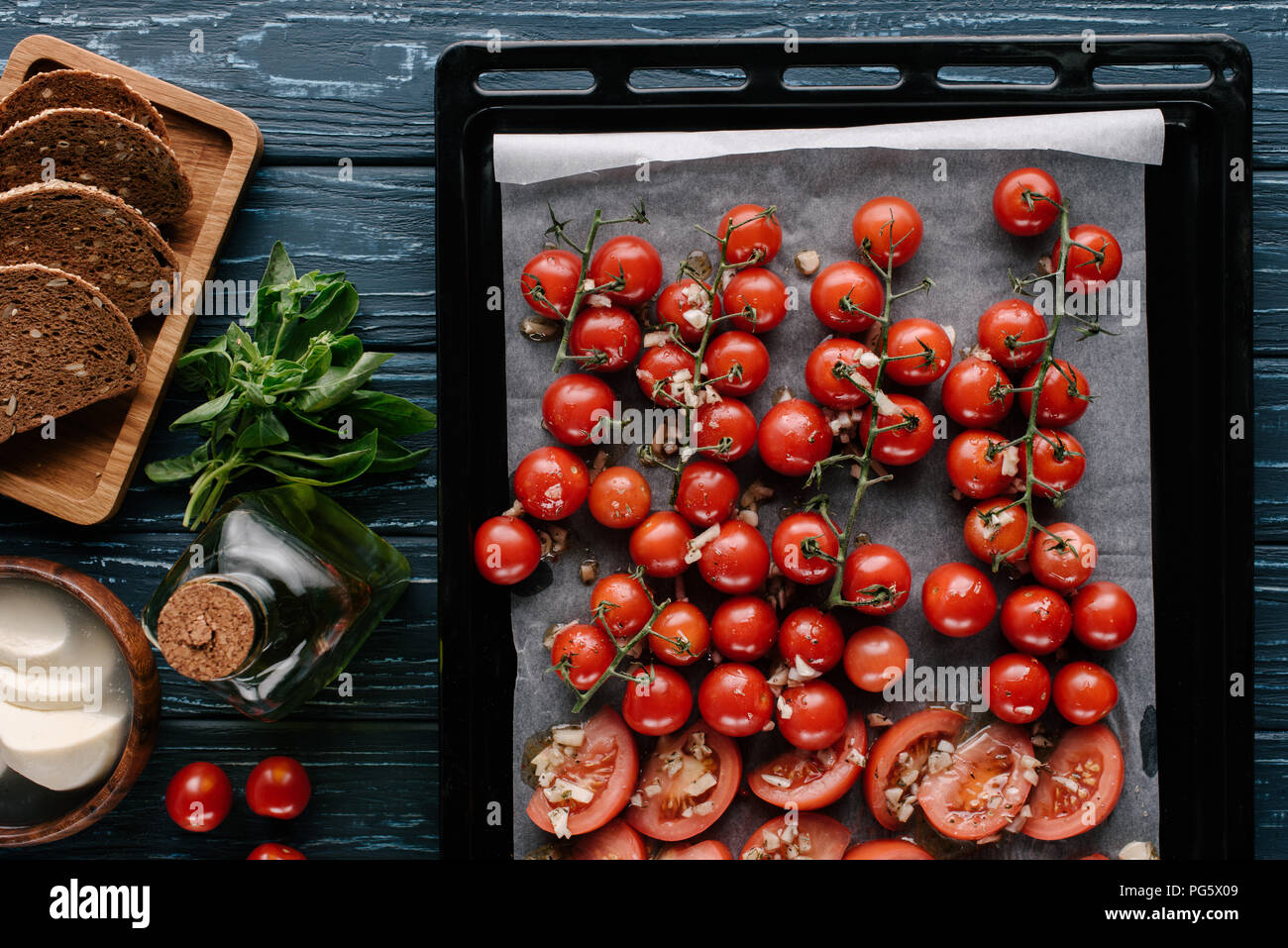 Baked cherry tomatoes with garlic and cheese on dark wooden table with ...