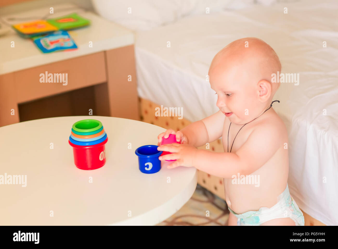 Cute little baby boy playing with stacking cups in the room Stock Photo