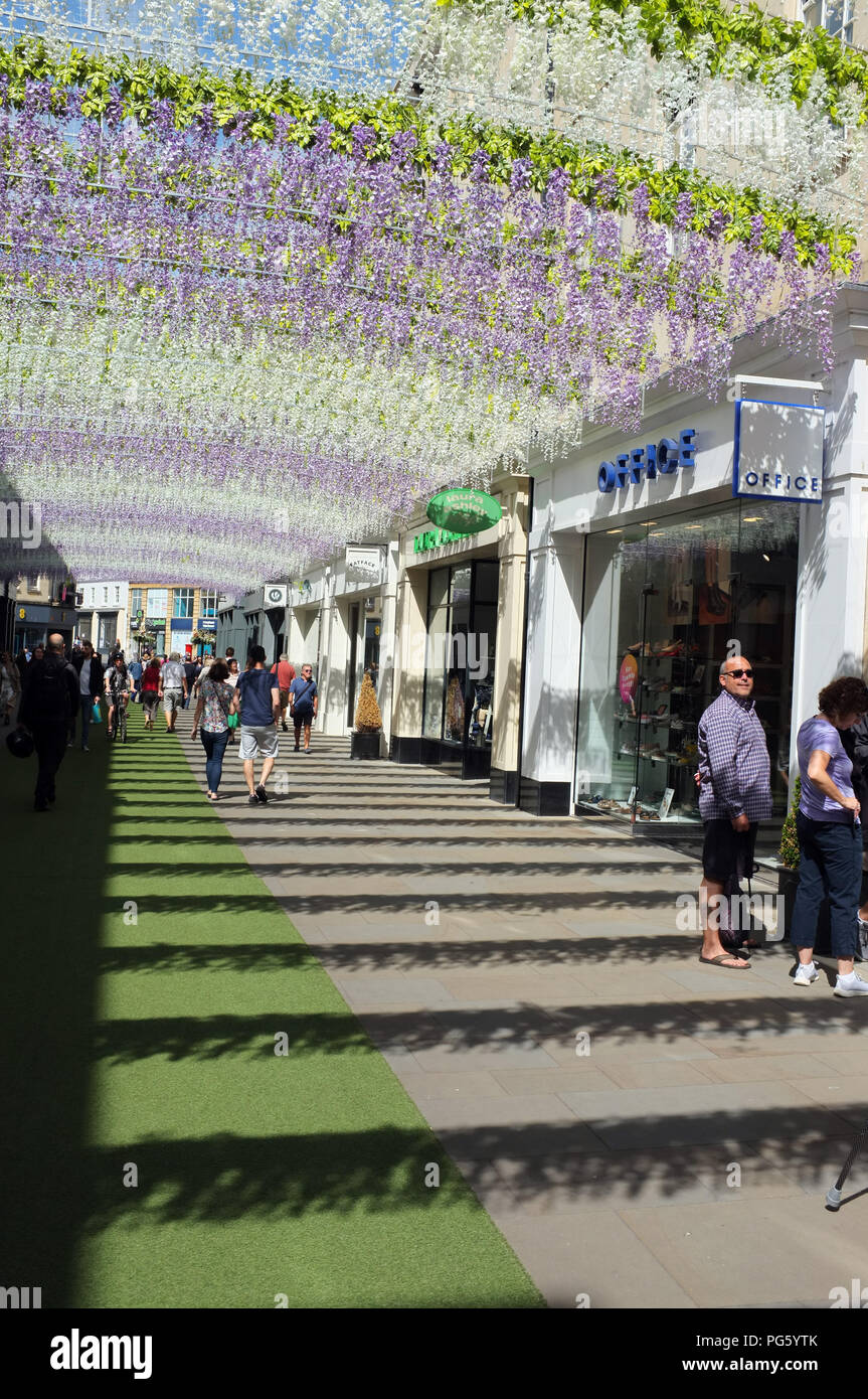 Shoppers walk underneath street art hanging above the main shopping