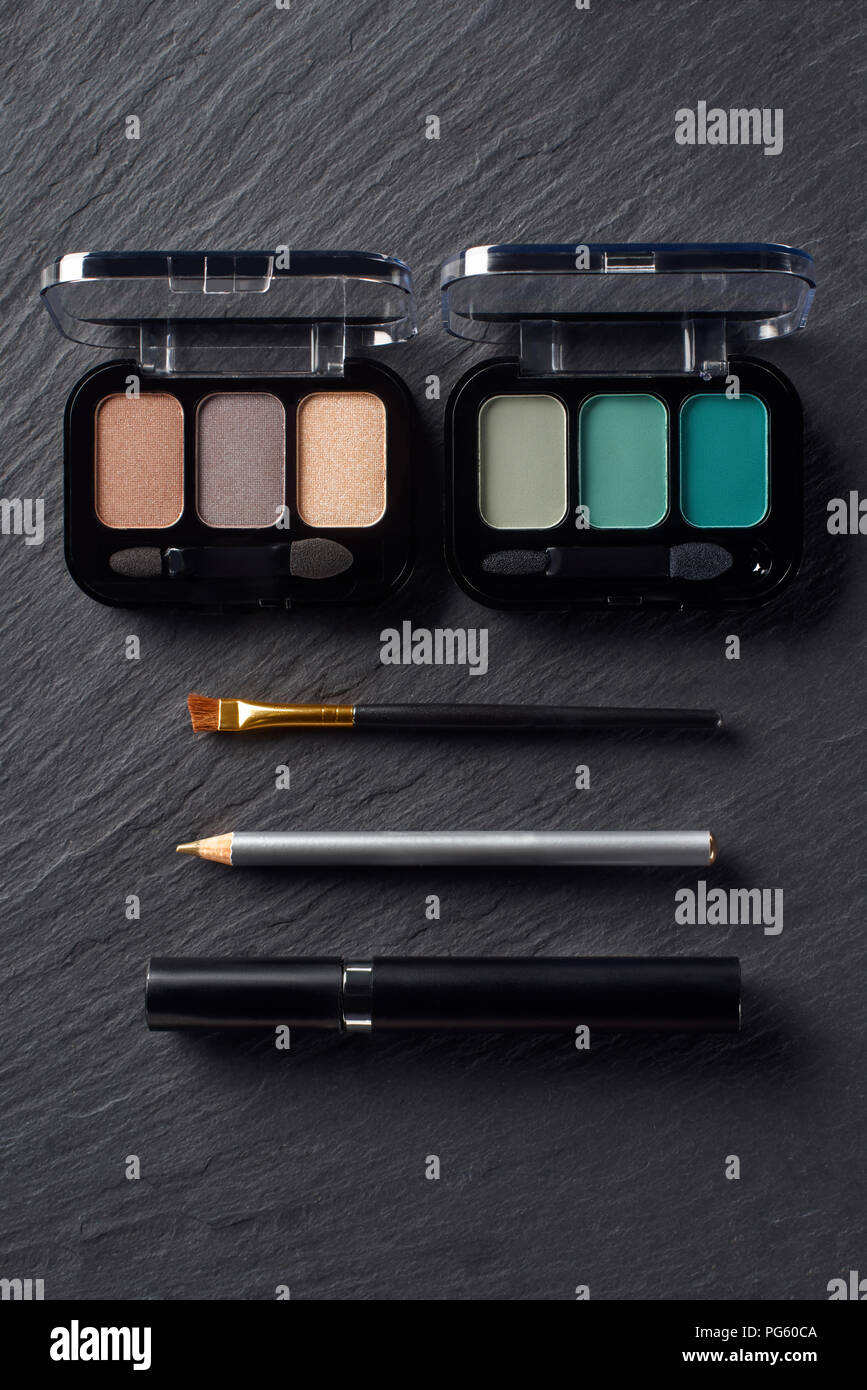 Palettes with eye shadows, pencil and mascara on dark slate background Stock Photo
