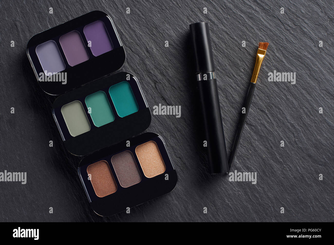 Make up palettes with mascara and brush on dark slate background Stock Photo