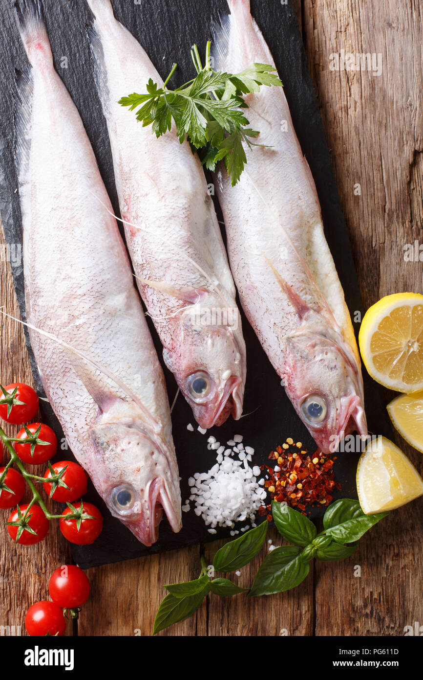 Raw Forkbeard or mostella fish with ingredients close-up on the table. Vertical top view from above Stock Photo