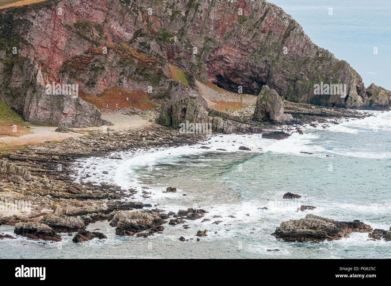 A rocky shoreline with red rock cliffs in the background Stock Photo