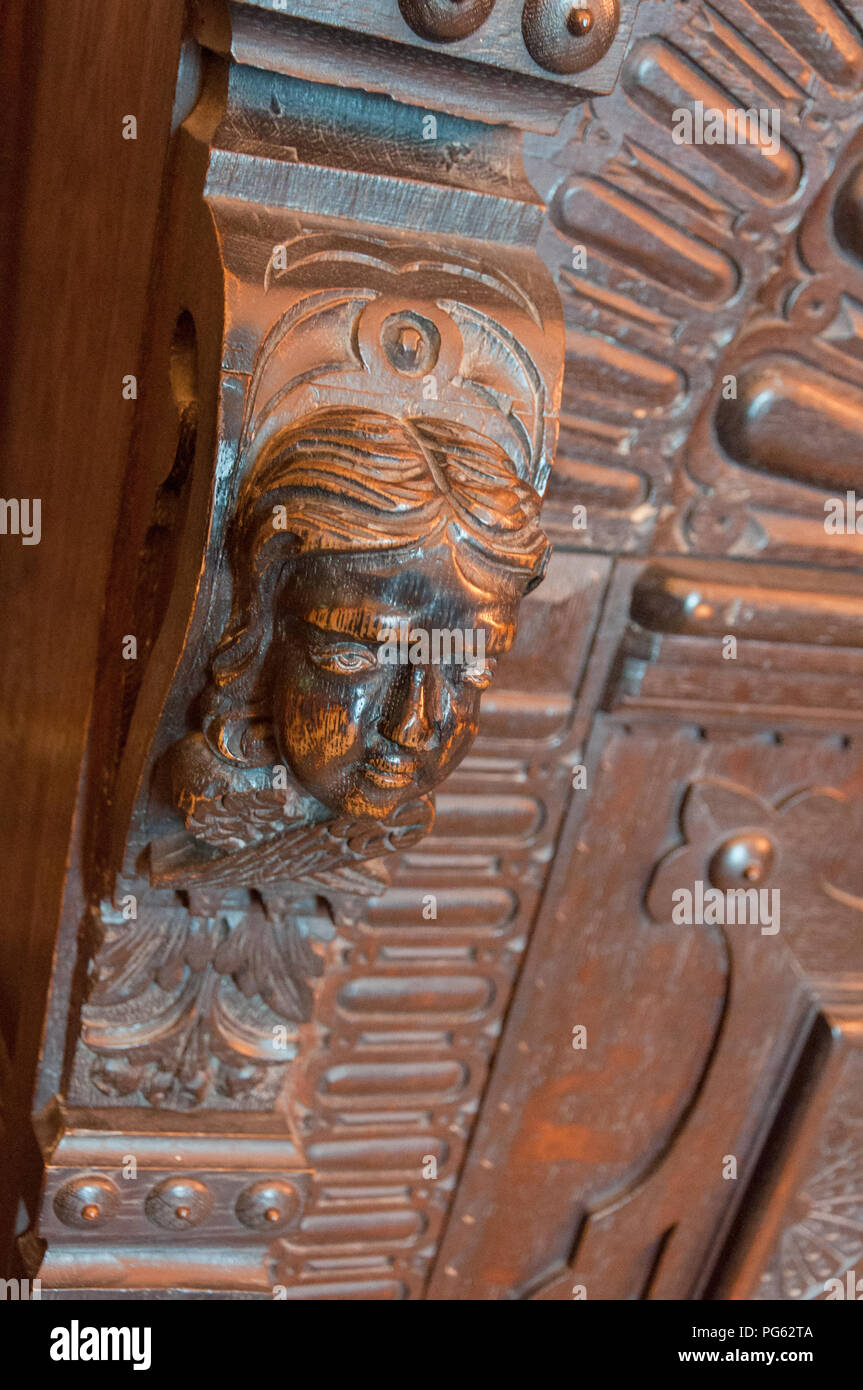 A head carved out of wood, part of a wooden cabinet in Bamburgh Castle, Northumberland, England, UK Stock Photo
