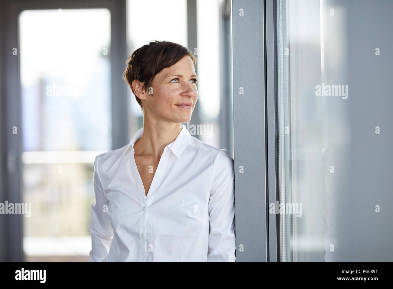 Smiling businesswoman in office looking sideways Stock Photo