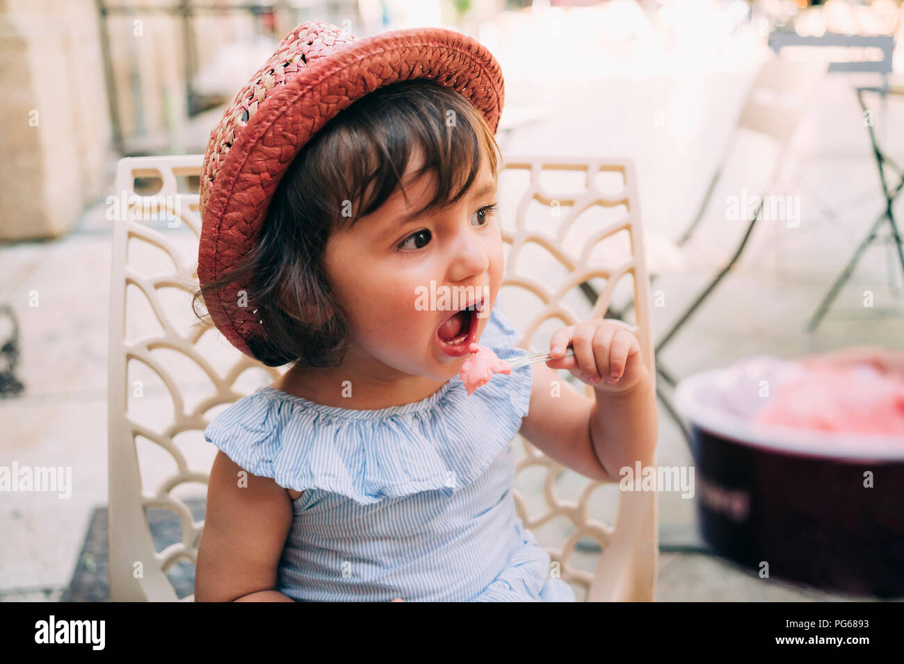 Cute toddler girl eating an ice cream on a terrace Stock Photo