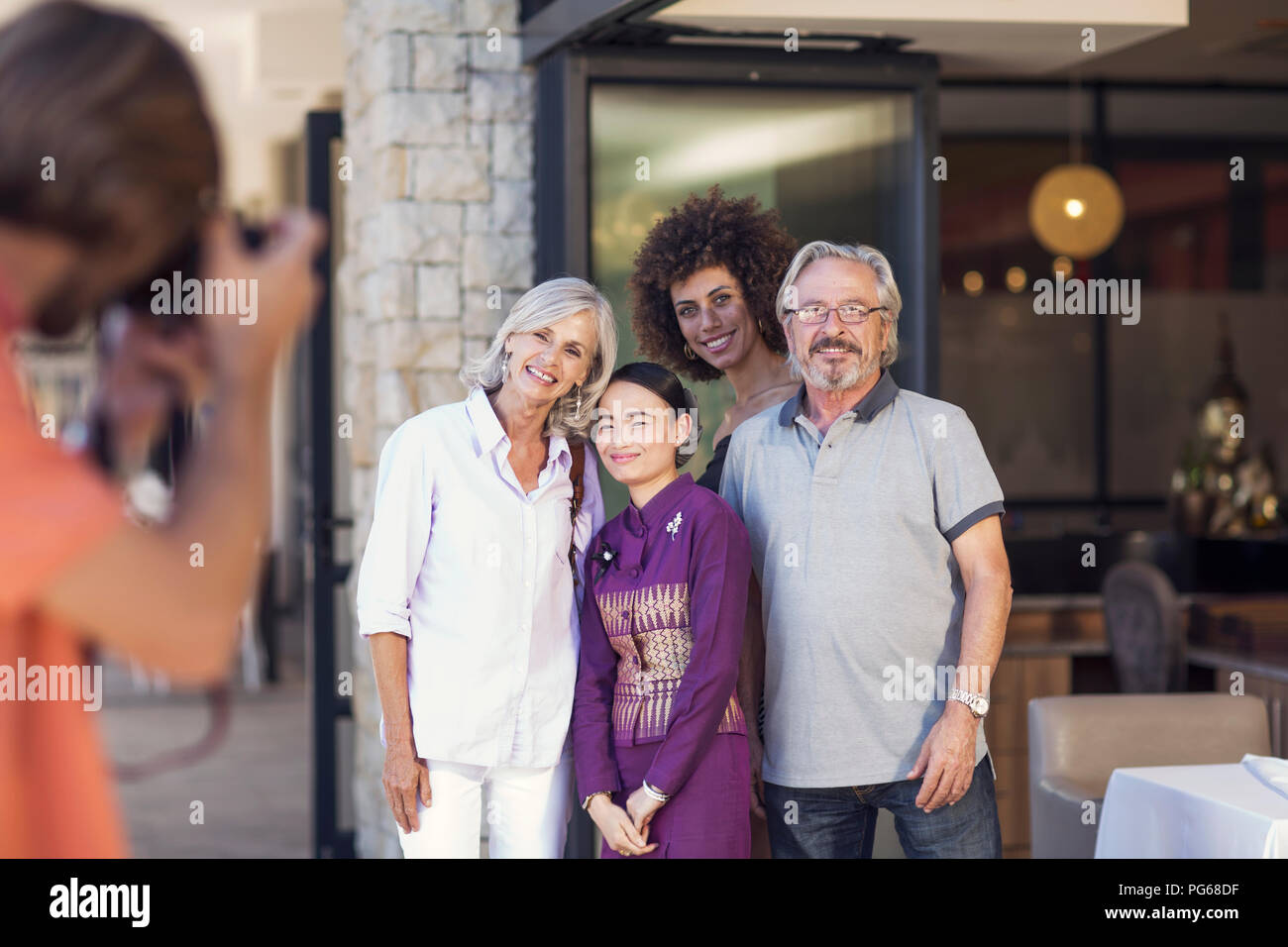 Family taking pictures with Asian waitress in front of restaurant Stock Photo