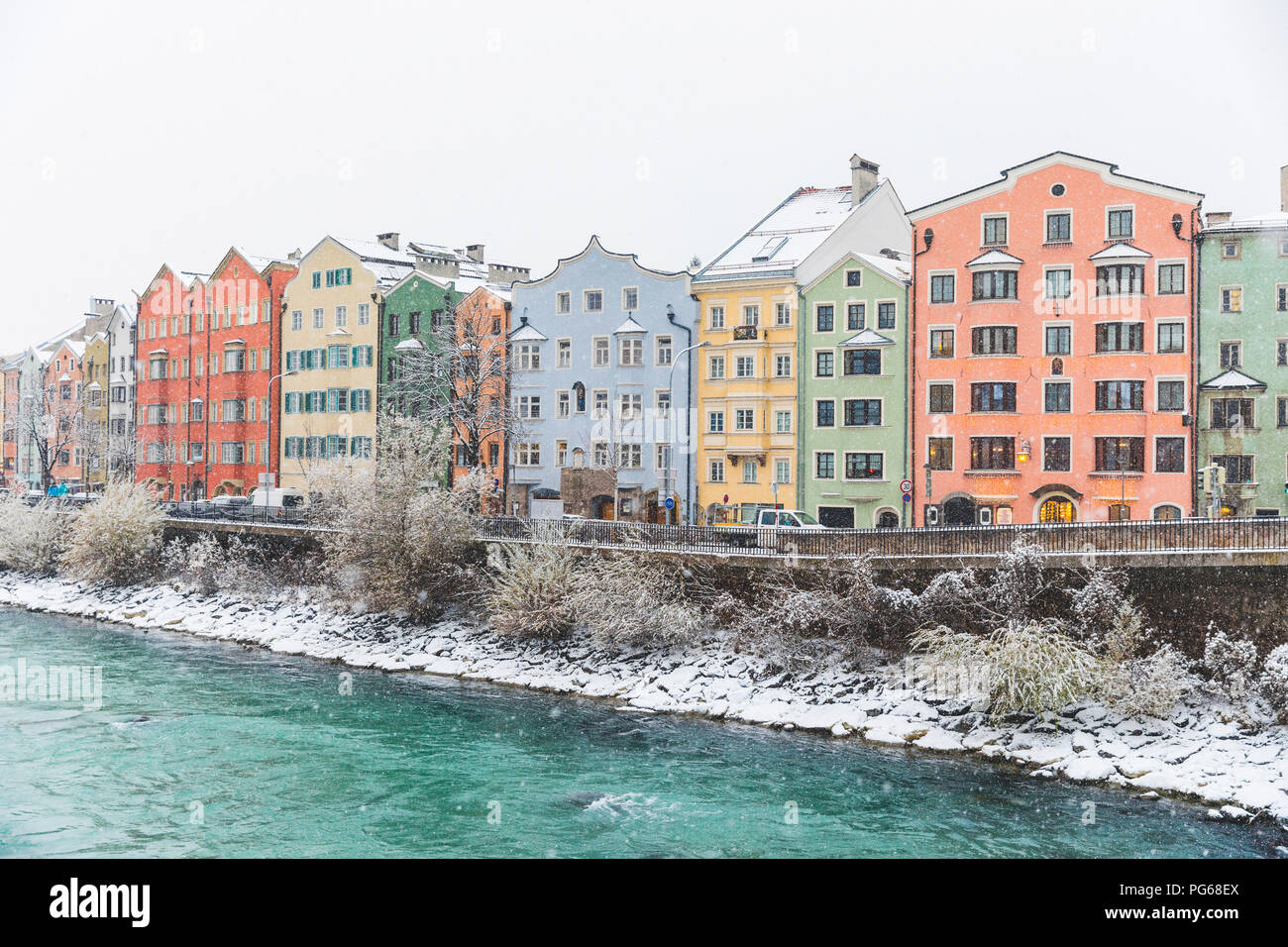 Austria, Innsbruck, row of colourful houses in winter with Inn River in the foreground Stock Photo