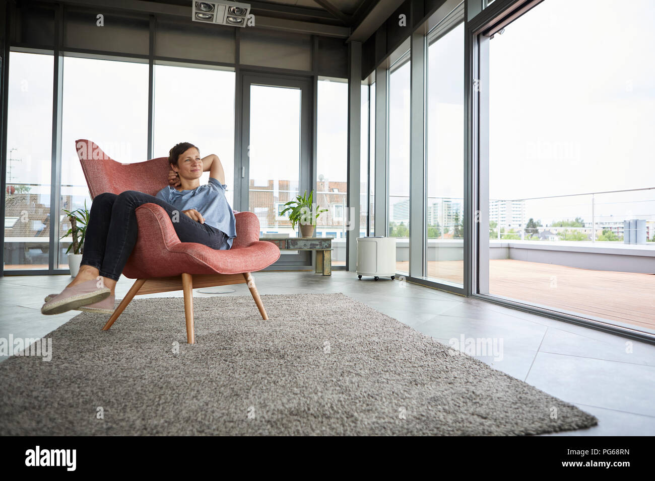 Woman sitting in armchair at home relaxing Stock Photo