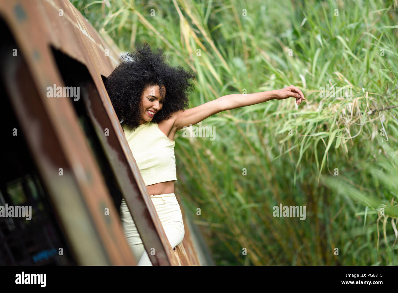 Fashionable young woman leaning out of abandoned and destroyed old train Stock Photo