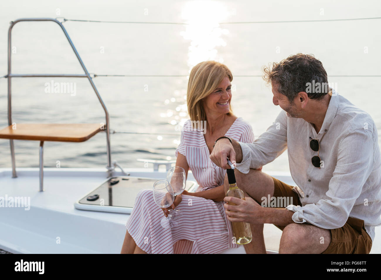 Mature couple drinking wine at sunset on a sailing boat Stock Photo